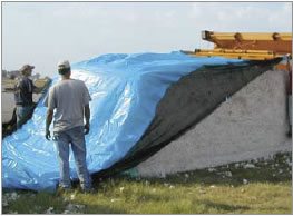 Figure 13 Covering a module by using the builder to pull the cover over the module. The front edge of the cover is attached temporarily to the door as the builder is driven forward.